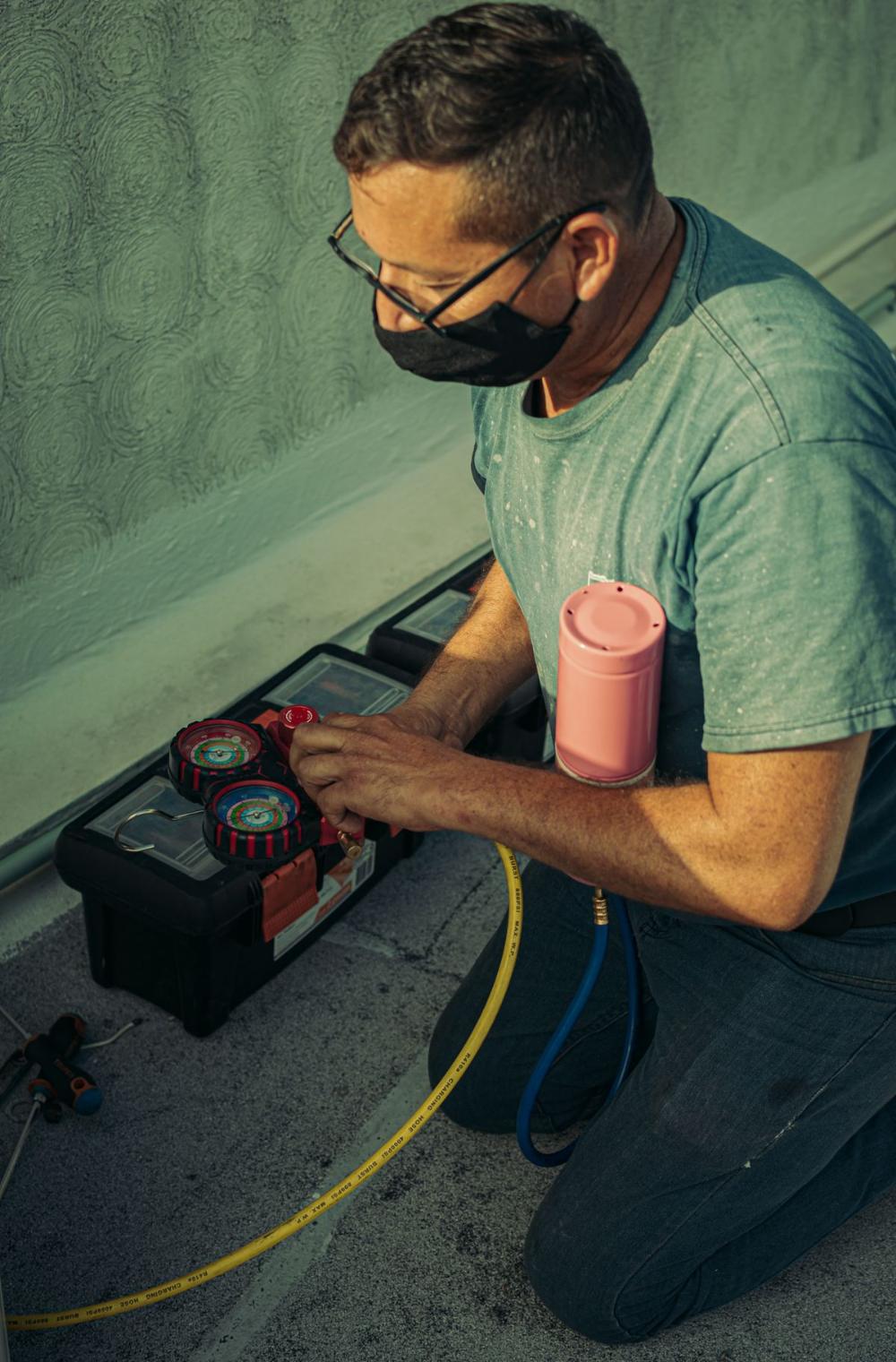Technician checking refrigerant pressures on an air conditioner