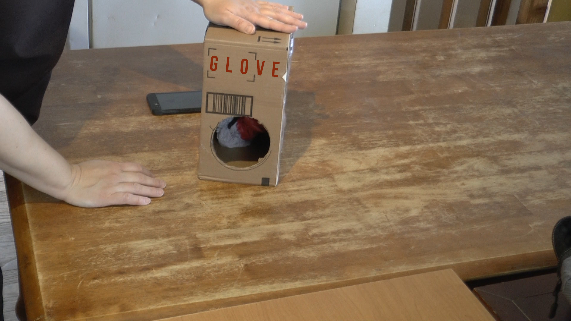 a gloved hand touches the top of a card board box