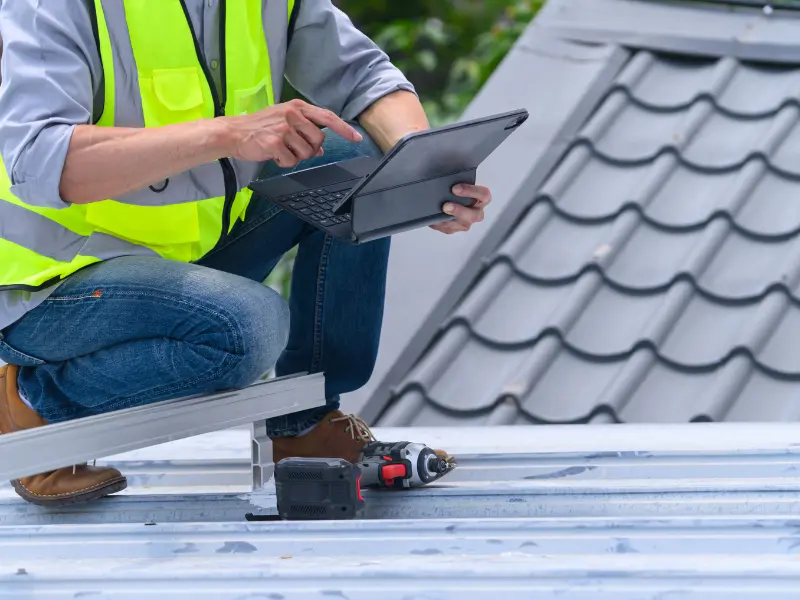Roof inspector reviewing metal roof condition on a tablet.