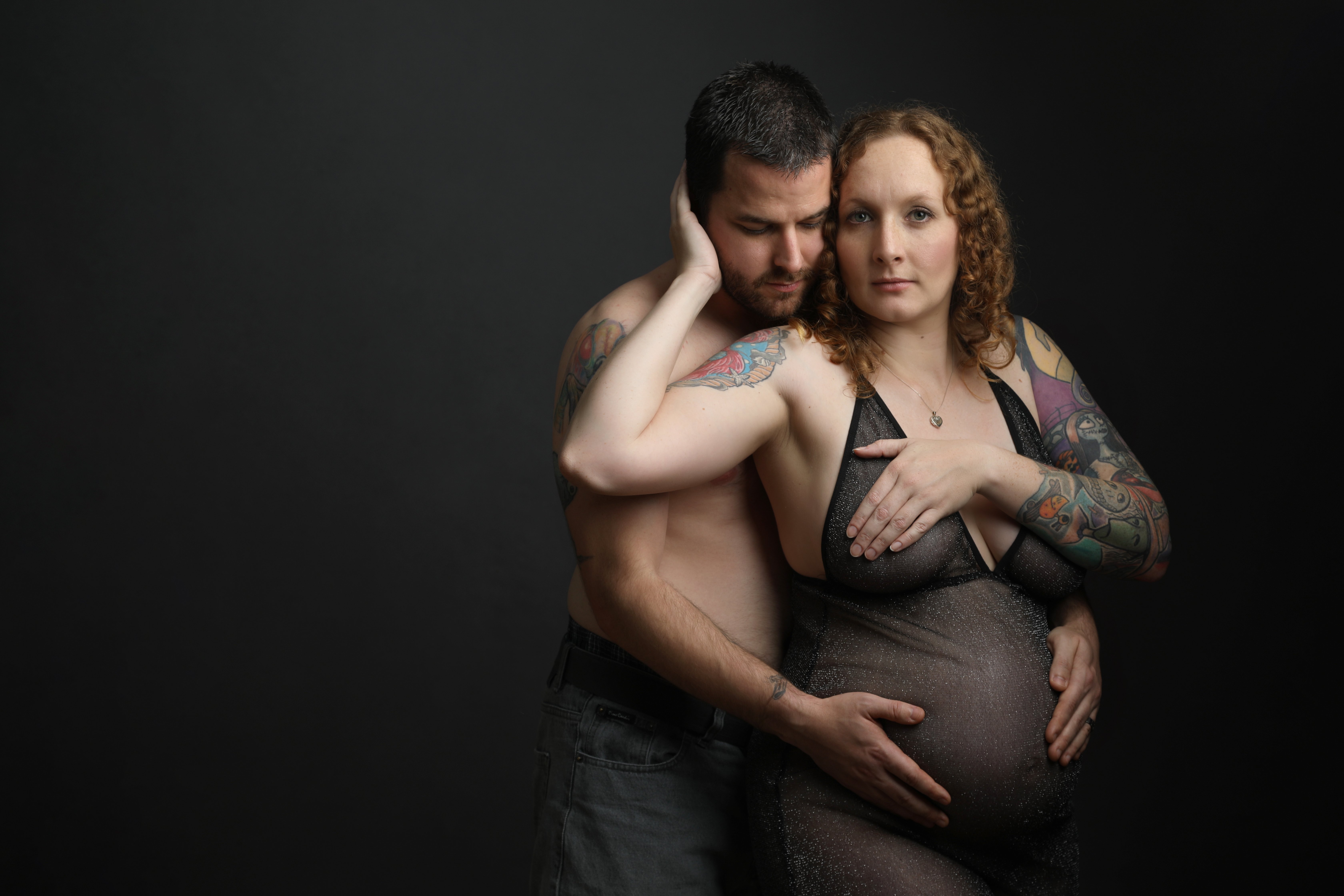 Husband and wife holding wife's bump - taken by professional photographer in Loughborough