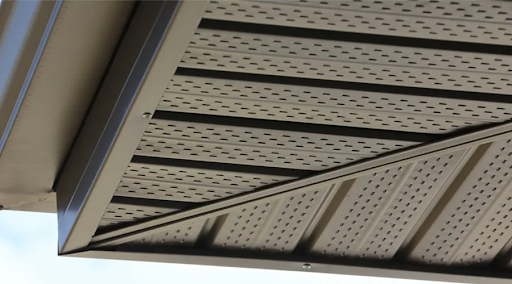 Perforated aluminum soffit panels installed on a residential roof overhang for attic ventilation.