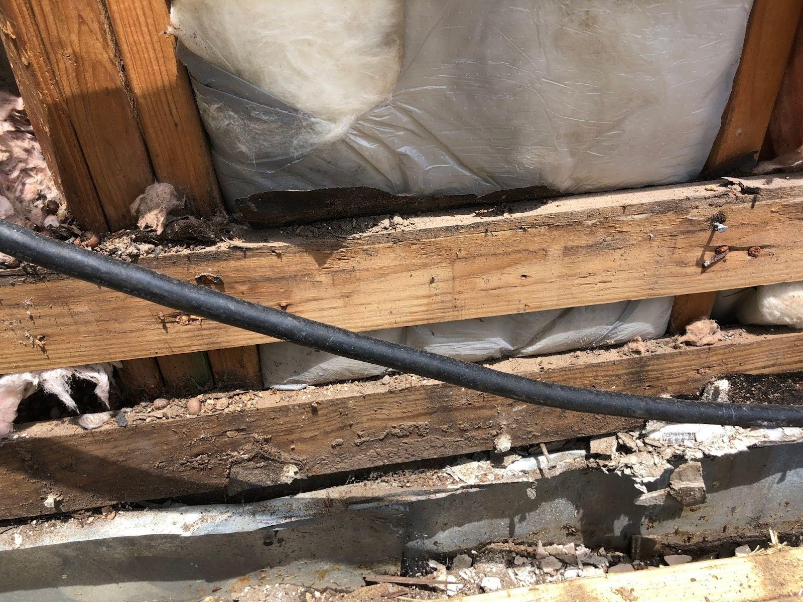 Structural wood rot and framing damage inside exterior wall caused by prolonged water intrusion from damaged or improperly functioning eavestroughs.