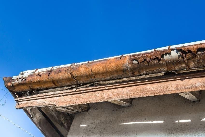 Severely damaged and rusted eavestrough system with holes and corrosion causing improper roof drainage and potential water damage to the home.