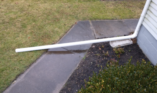 Downspout extension blocking a sidewalk and needing a professional drainage