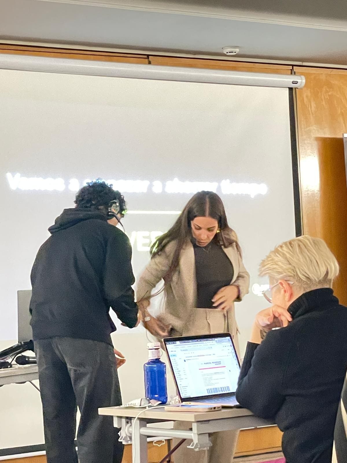Lilia San Juan ayudando a dos asistentes con su portátil