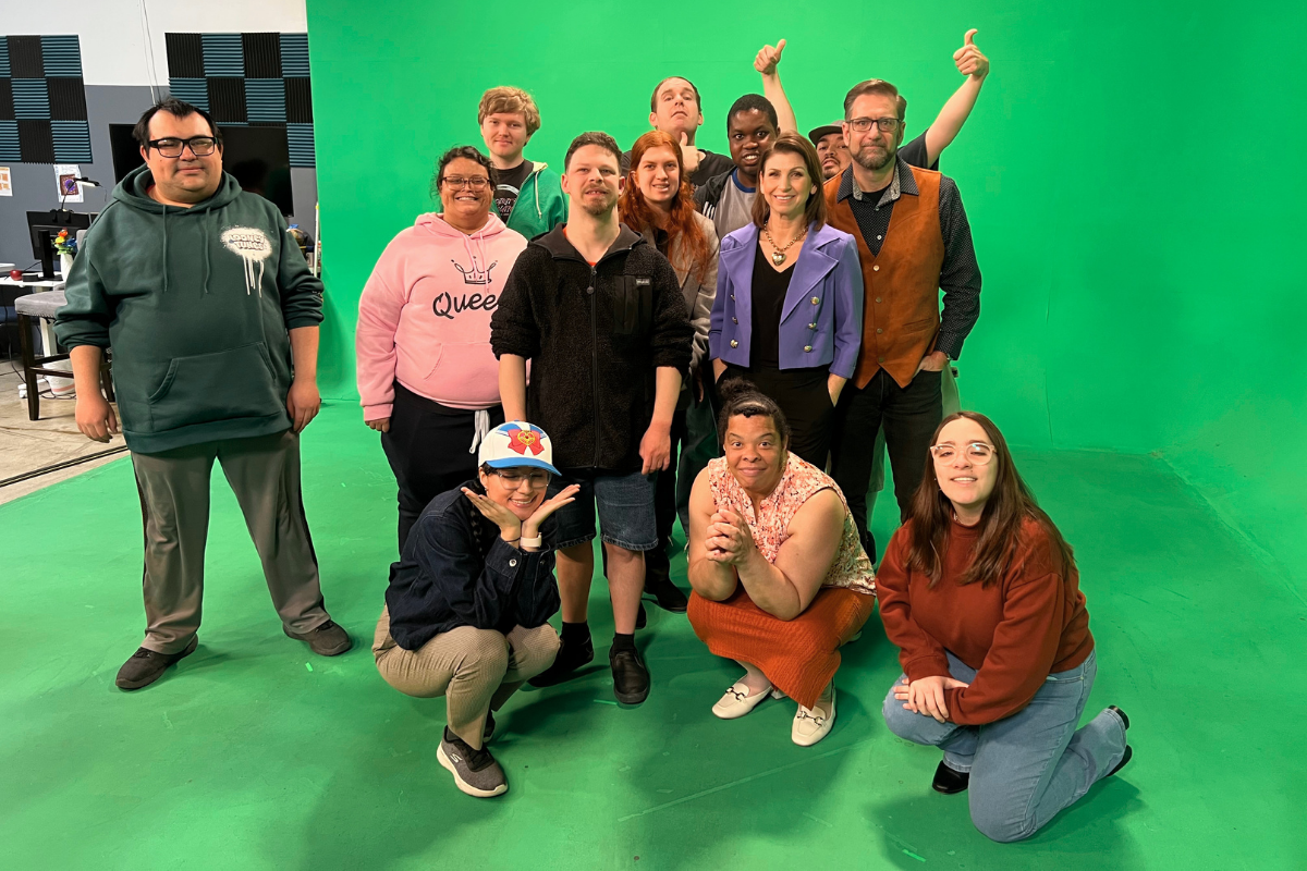 Students collaborating with cameras, scripts, sound equipment, and video editing tools during a hands-on creative production class.