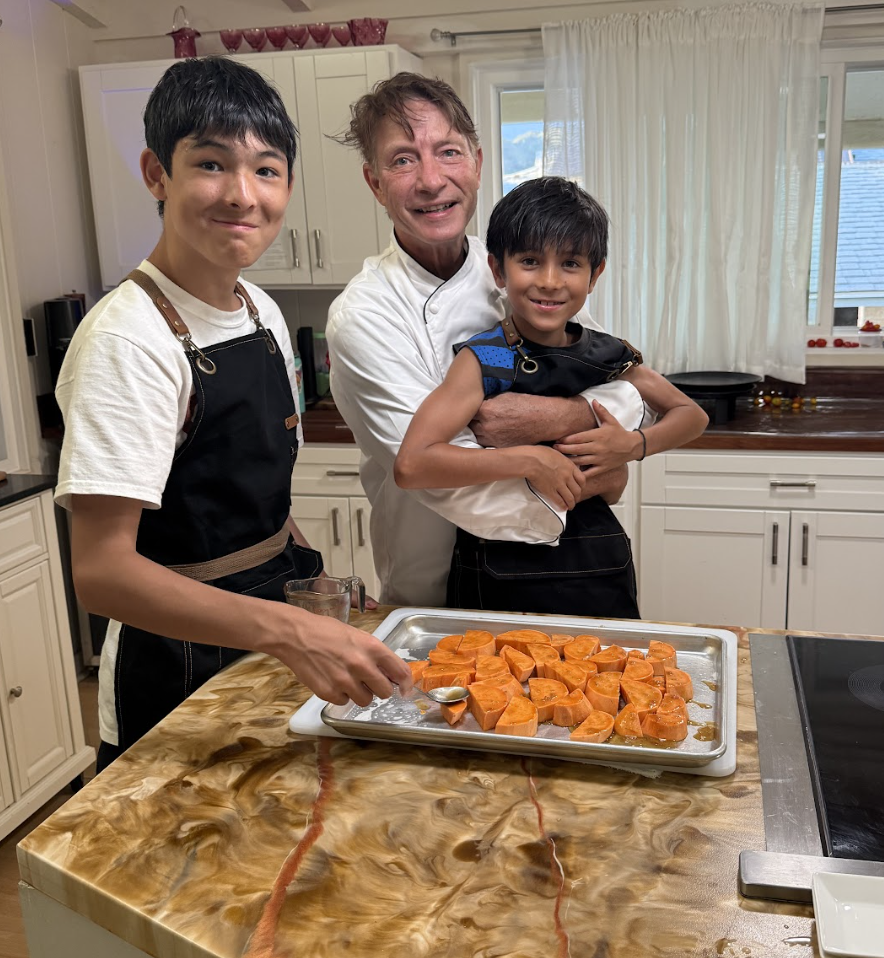 Chef David Paul with two young students and a tray of food in the kitchen