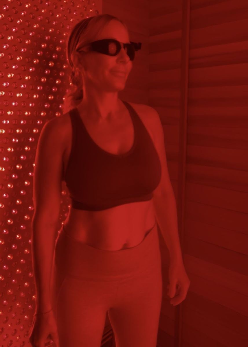 A fit, smiling member in a red light therapy session