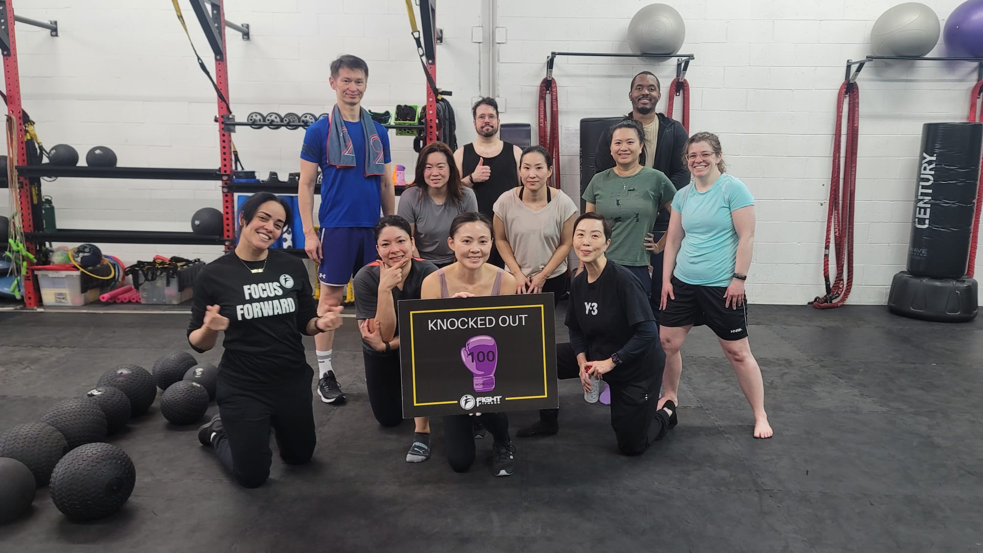Nelly “The Beast” celebrating with Fight Fitness members holding Knocked Out milestone signs inside the gym.