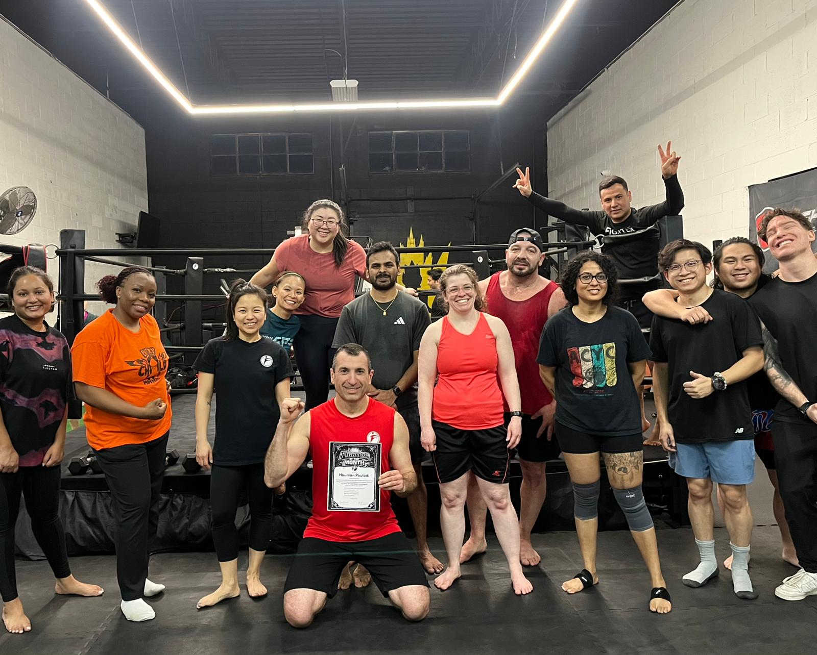 Houman Pouladi Fighter of the Month at Fight Fitness holding milestone board in gym