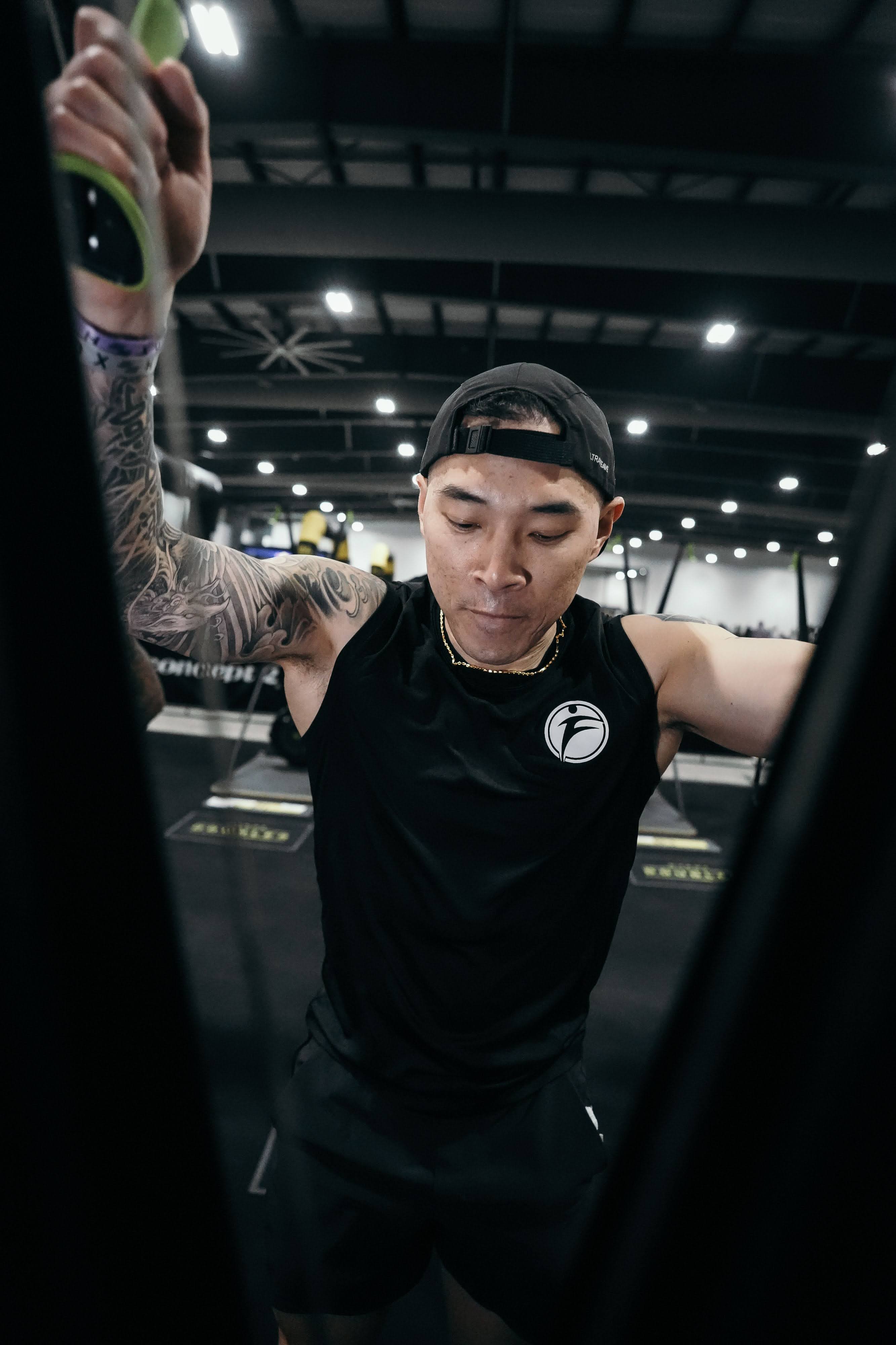 Joe Hsiung performing the ski erg station at Hyrox Ottawa 2026 Open Doubles competition. He is pulling down on the ski erg handles in a powerful motion inside the EY Centre arena with Hyrox branding and other competitors visible in the background.