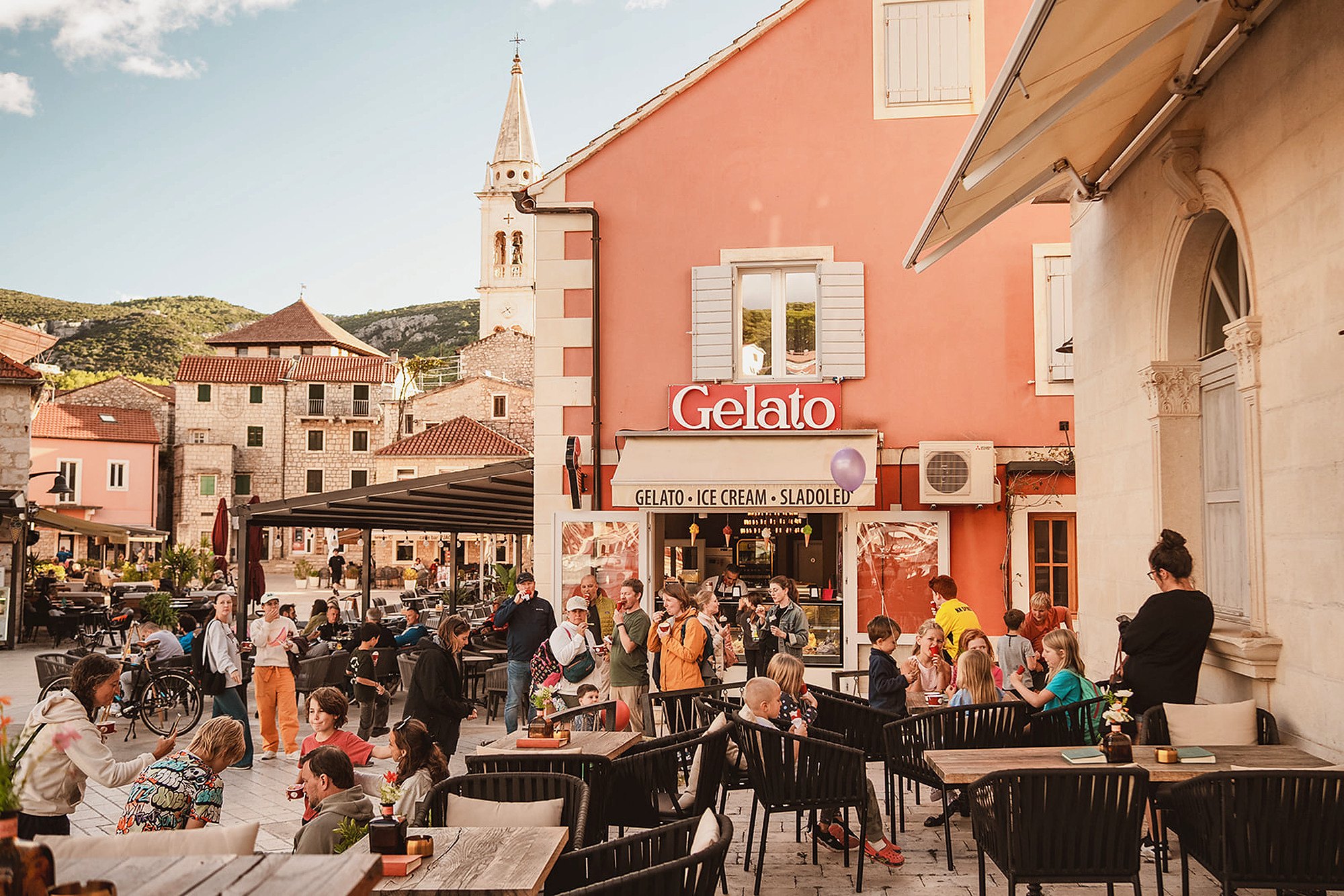 The main square in Jelsa, Hvar, early evening, with families outside the gelato shop