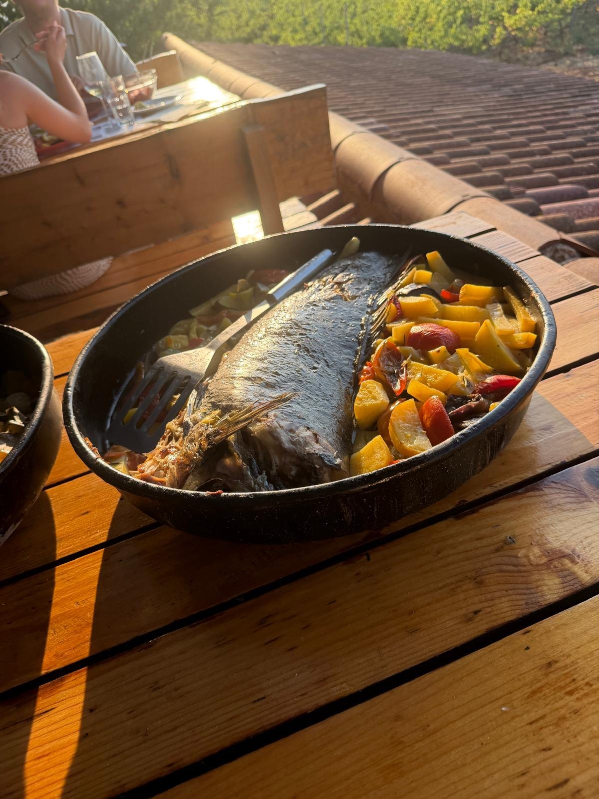 Baked fish and vegetables in a black pan