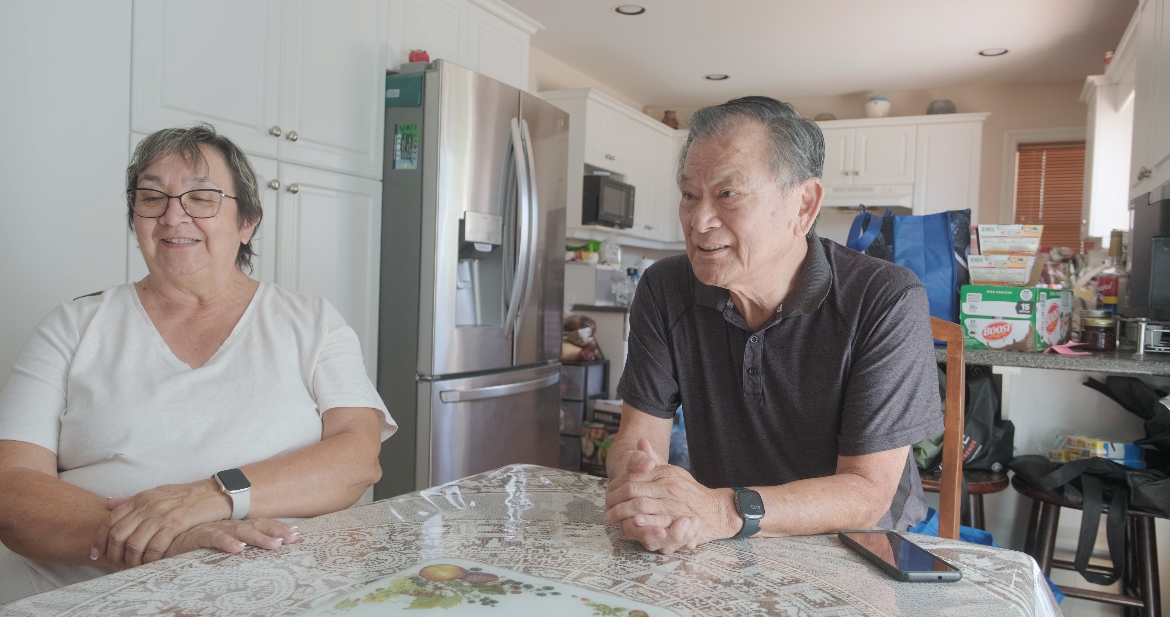 An elder speaking at a kitchen table
