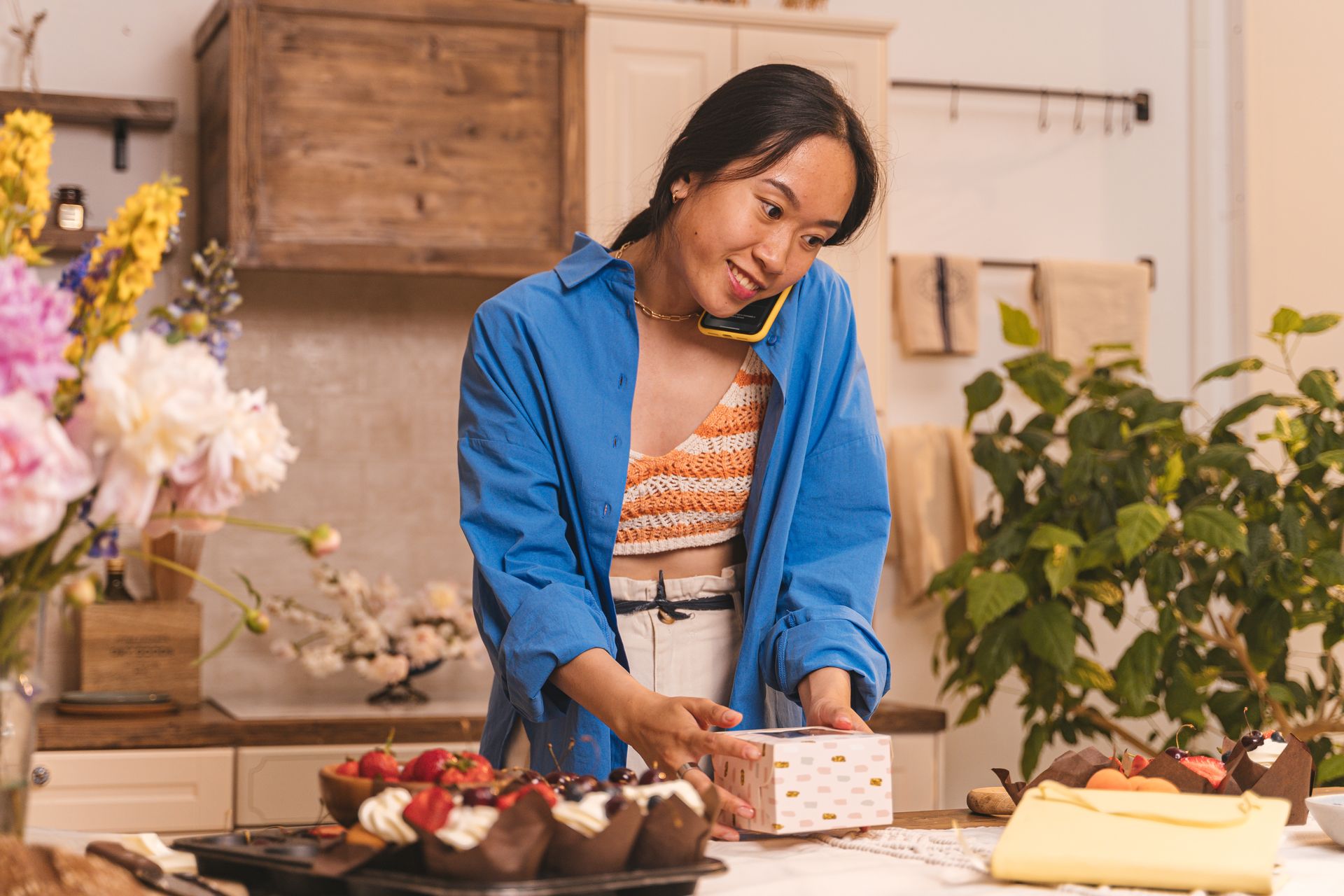Bakery owner boxing cupcakes while taking a phone order