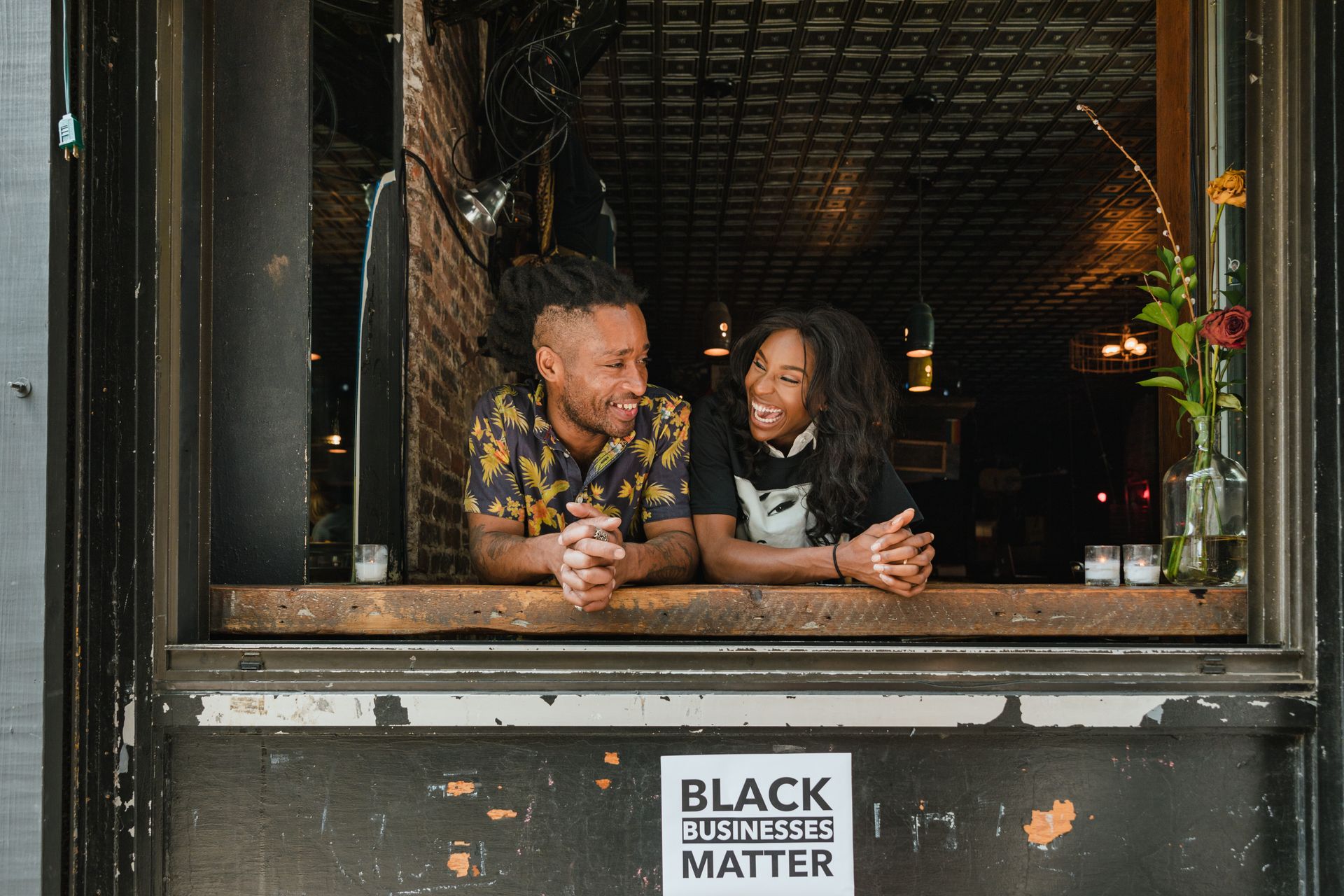 Two cafe owners laughing in their storefront window