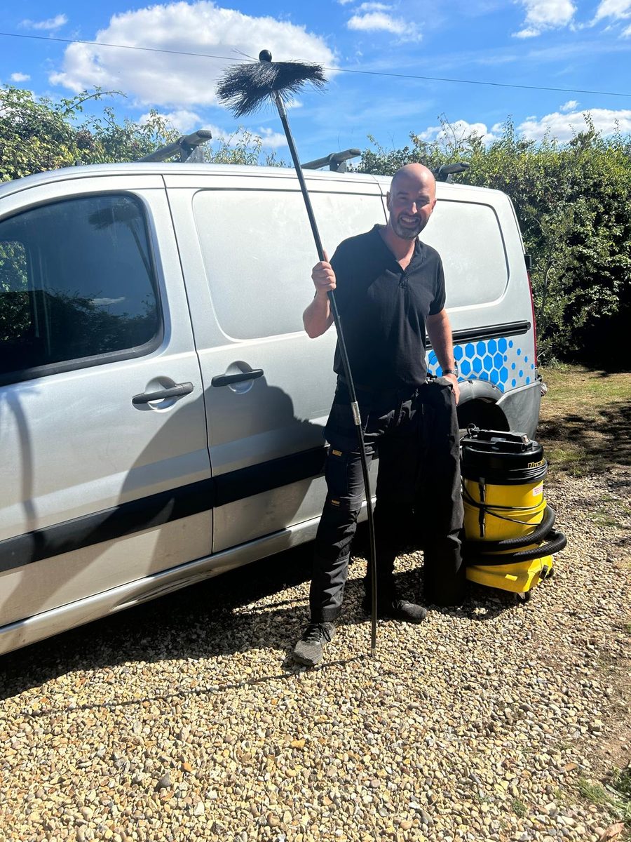 Graham Johns, HETAS registered chimney sweep, with a swept chimney and lit stove