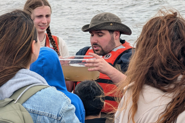 Billion Oyster Project educator showing students marine life collected from the shoreline habitat