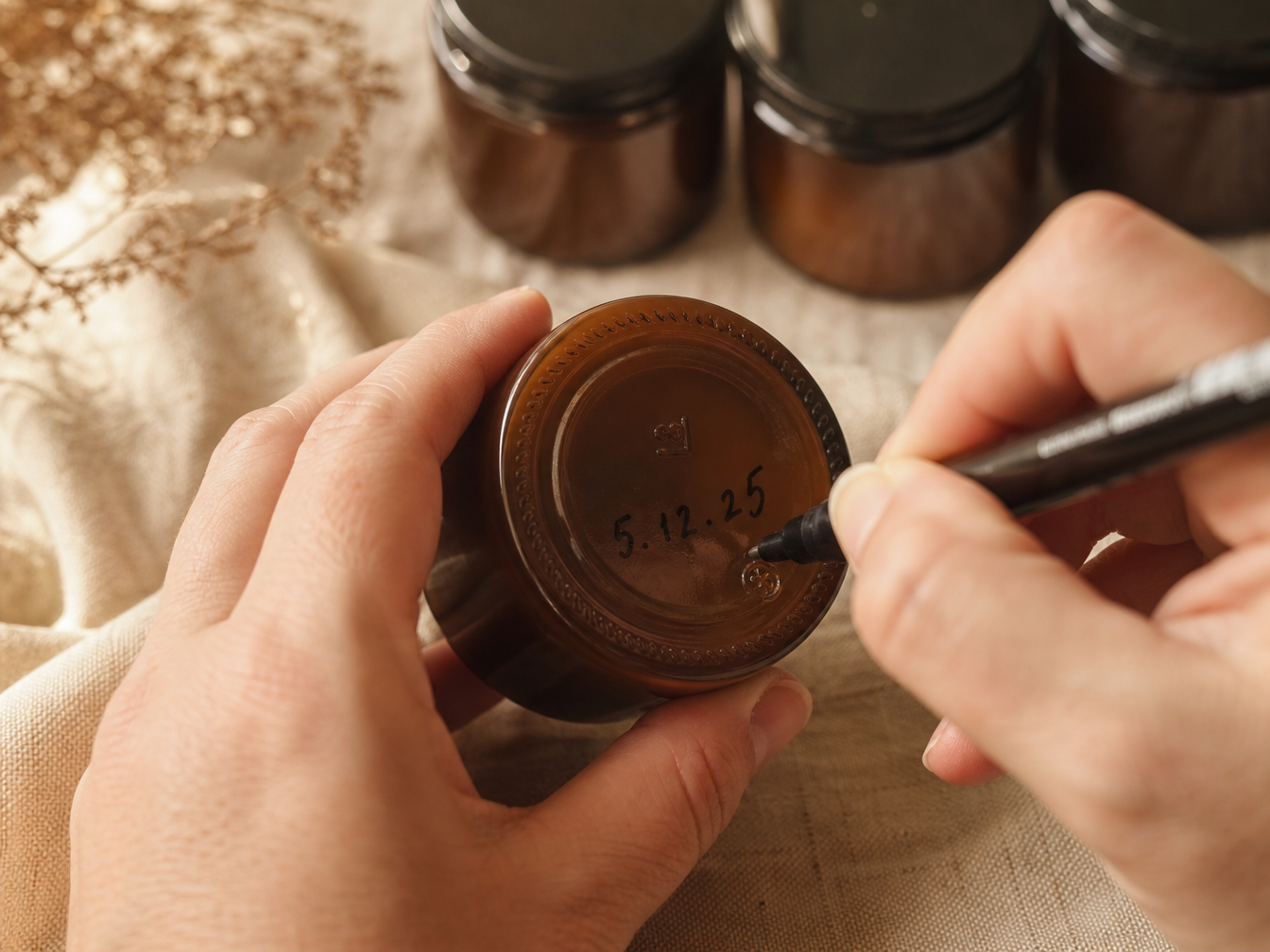 Hand writing batch date on Two Leaf Baby tin
