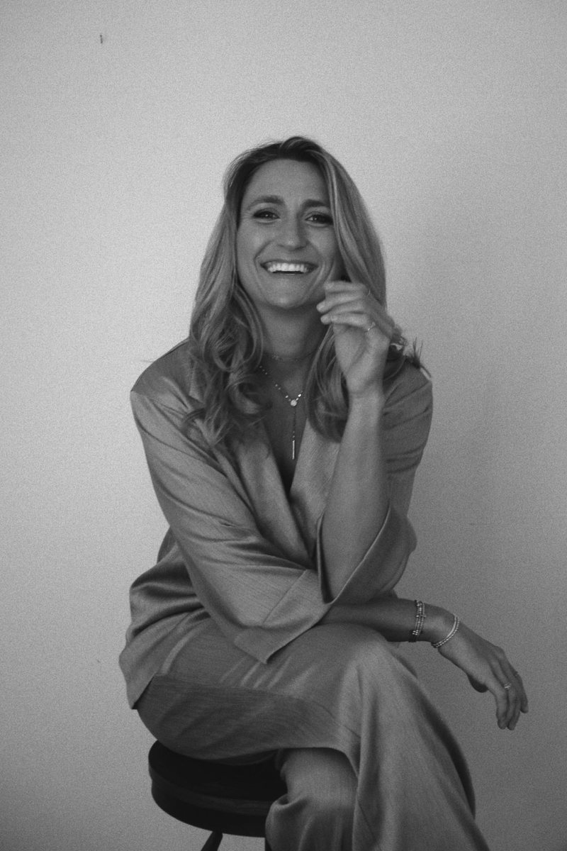Dallas Cole laughing, seated on a stool, in black and white