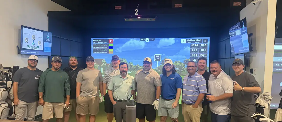 A group of golfers celebrating together in front of a simulator bay