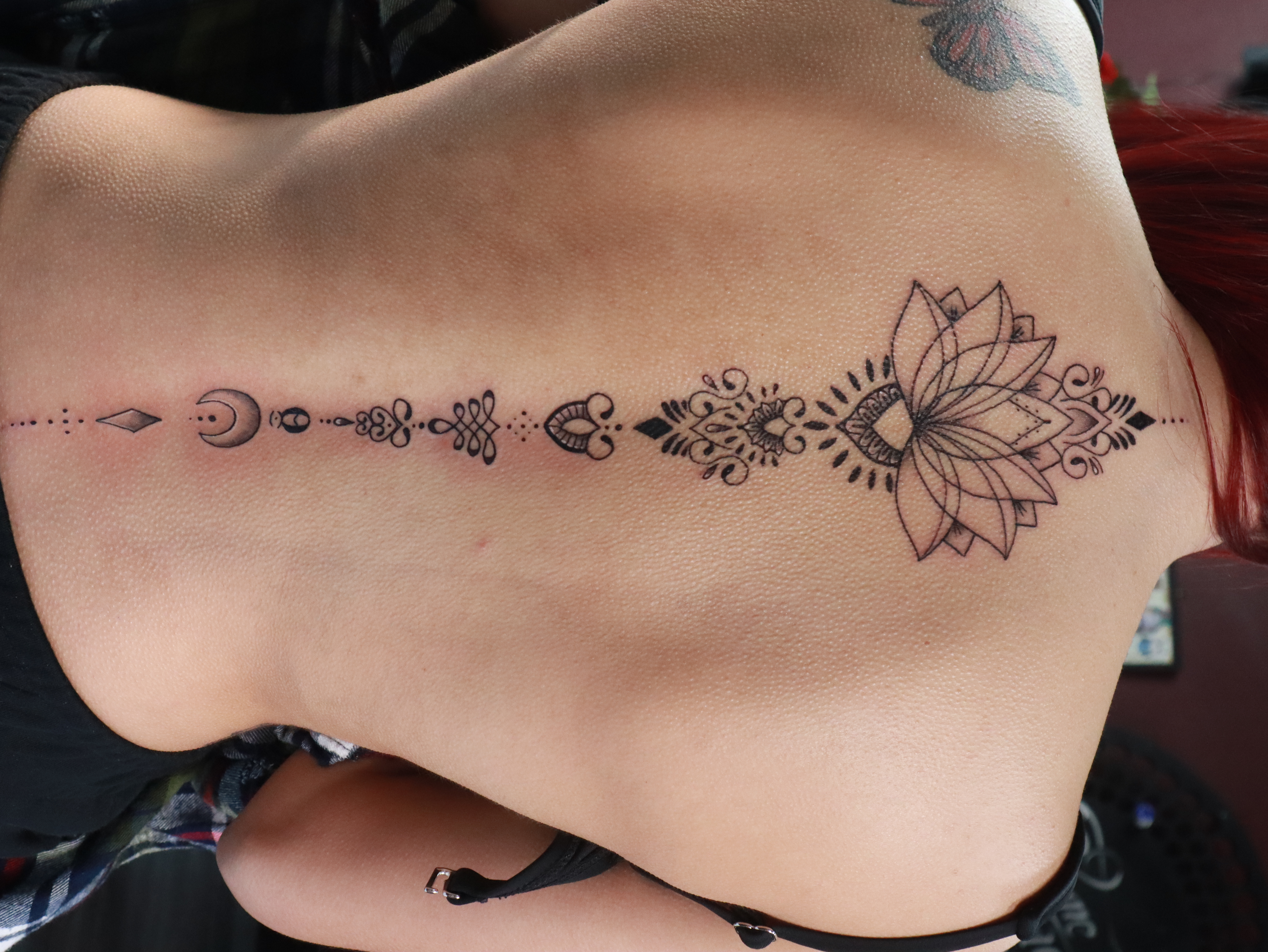 Lotus flower tattoo design on the back, featuring intricate line work and decorative elements, showcasing Droe's neotraditional style and artistic versatility.