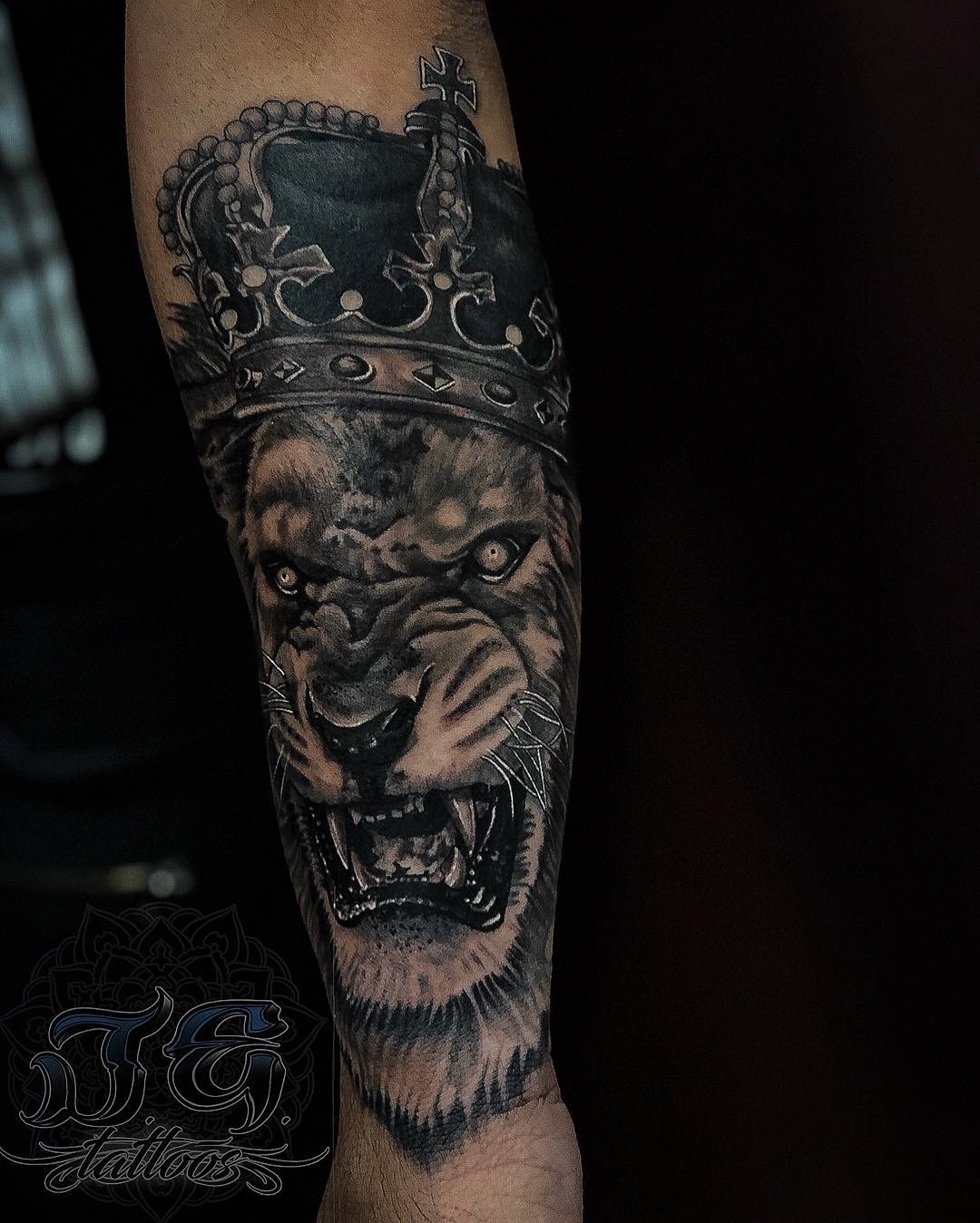 Detailed tattoo of a roaring lion wearing a crown on a forearm, showcasing Jest Estevez's artistry at GameFace Tattoos.