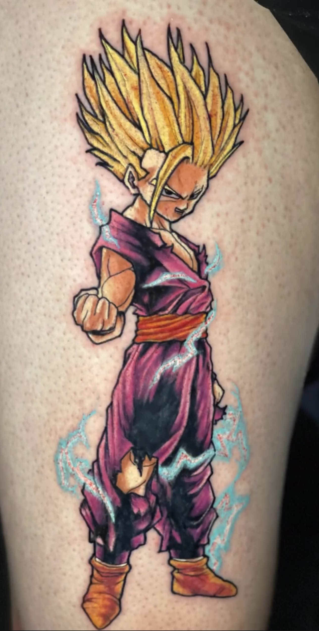 Tattoo of a dynamic anime character with spiky blonde hair and a determined expression, wearing a purple outfit, showcasing vibrant colors and intricate details, reflecting the artistic style of tattoo artist Alex from GameFace Tattoo.