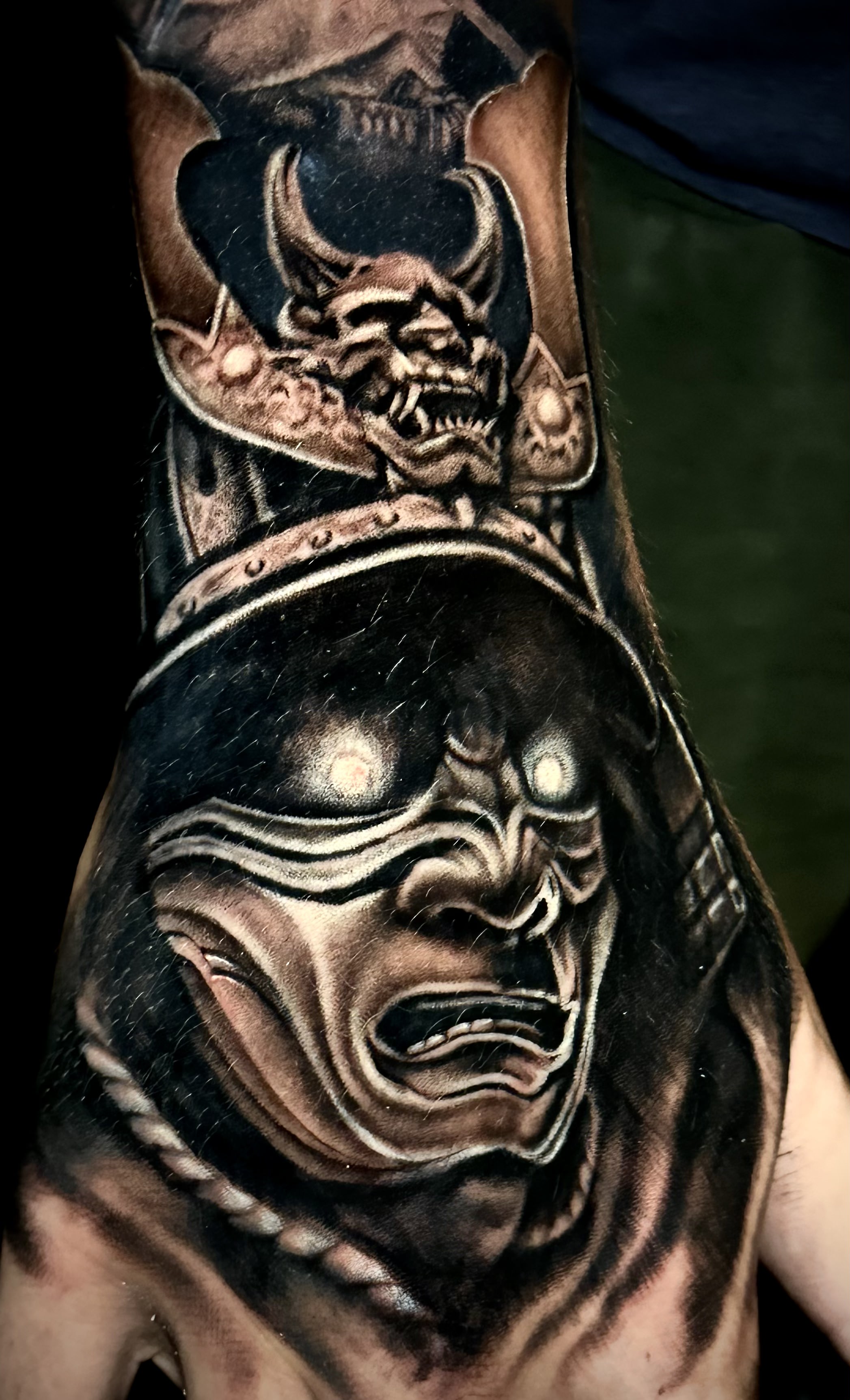 Detailed tattoo of a fierce warrior's face with an intricate helmet and menacing expression, showcasing Alex's artistry at GameFace Tattoo.