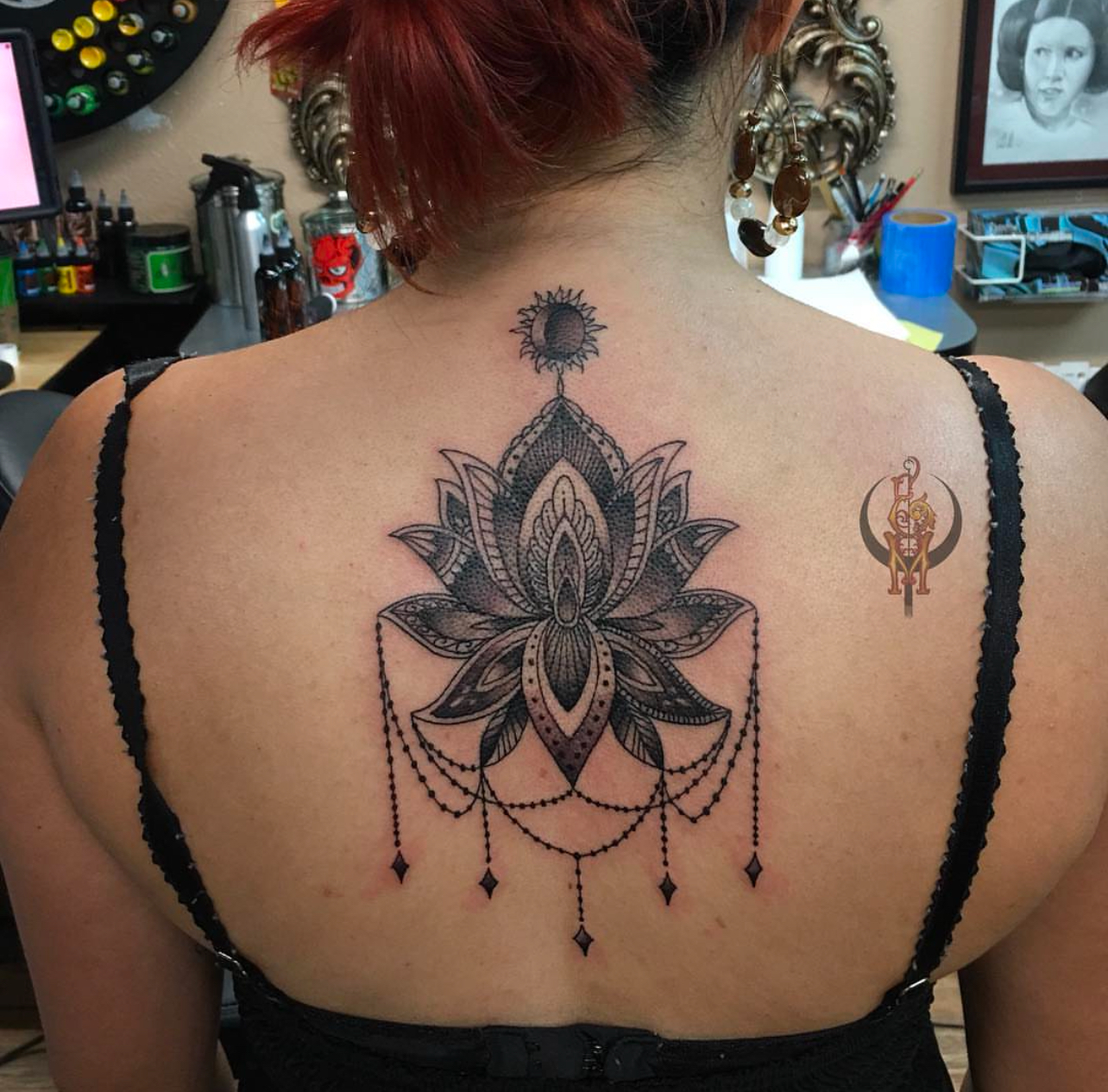 Lotus flower tattoo with intricate details on a woman's back, featuring decorative elements and a small sun above, showcasing Edward Madera's tattoo artistry at GameFace Tattoo.