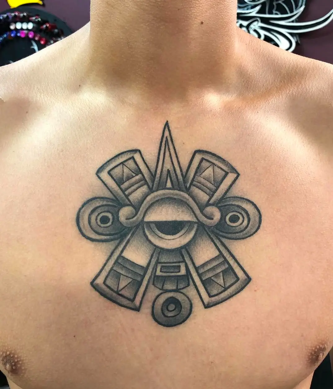 Tattoo design featuring intricate geometric patterns and an eye motif on a person's chest, showcasing artistry from GameFace Tattoo studio.