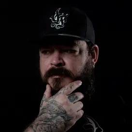 Tattoo artist with a beard and tattoos, wearing a cap, showcasing expertise and artistry in body art at GameFace Tattoos.