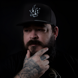 Tattoo artist wearing a cap and black shirt, showcasing expertise in body art at GameFace Tattoos studio in Orlando.