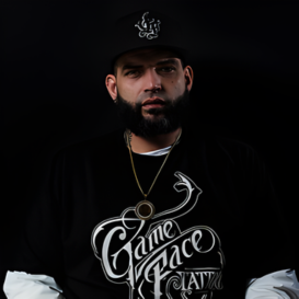 Master artist from GameFace Tattoos wearing branded apparel, showcasing body art expertise in a studio setting.