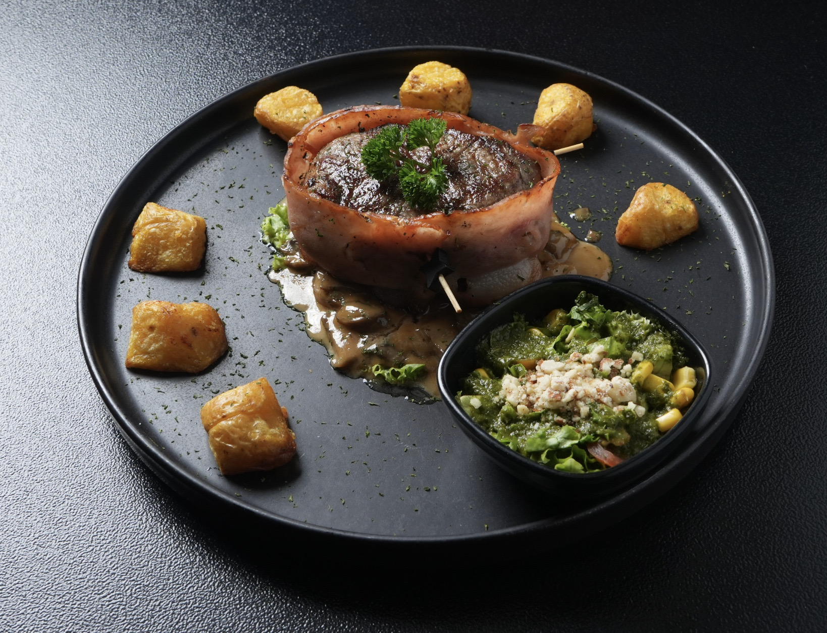 Filet Mignon envuelto en tocineta sobre plato negro