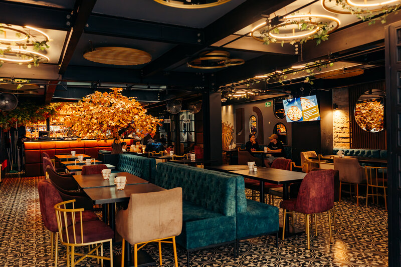 Salón principal con árbol dorado icónico, barra iluminada y piso de mosaico