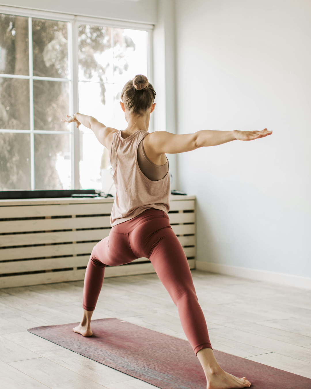 Une femme fait du yoga de dos, sur un tapis rouge