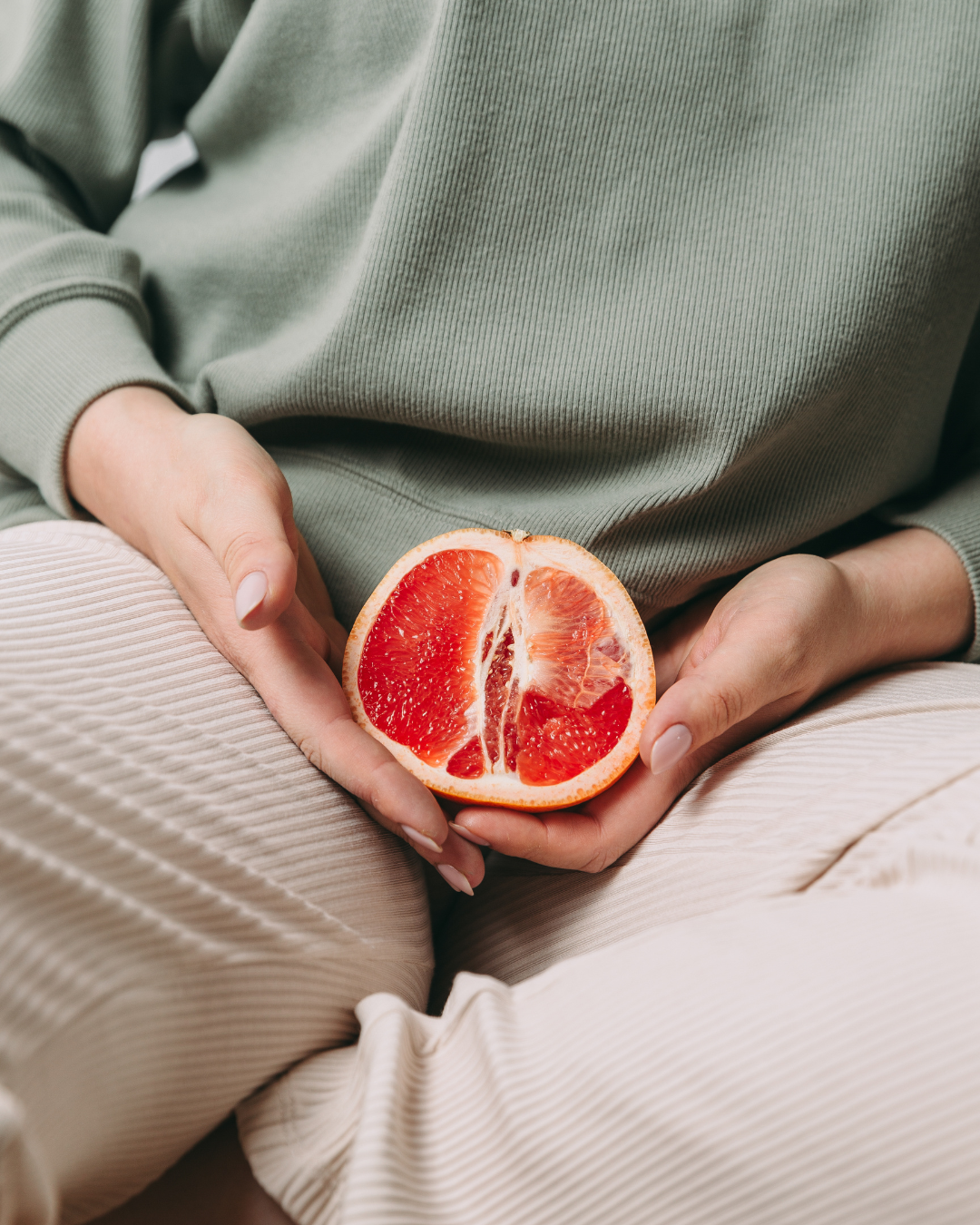 Une femme tient une agrume sur son pubis