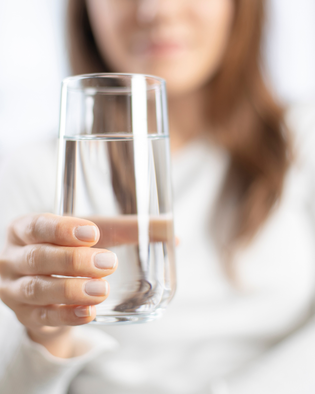 Une verre d'eau au focus, il est tenu par une femme