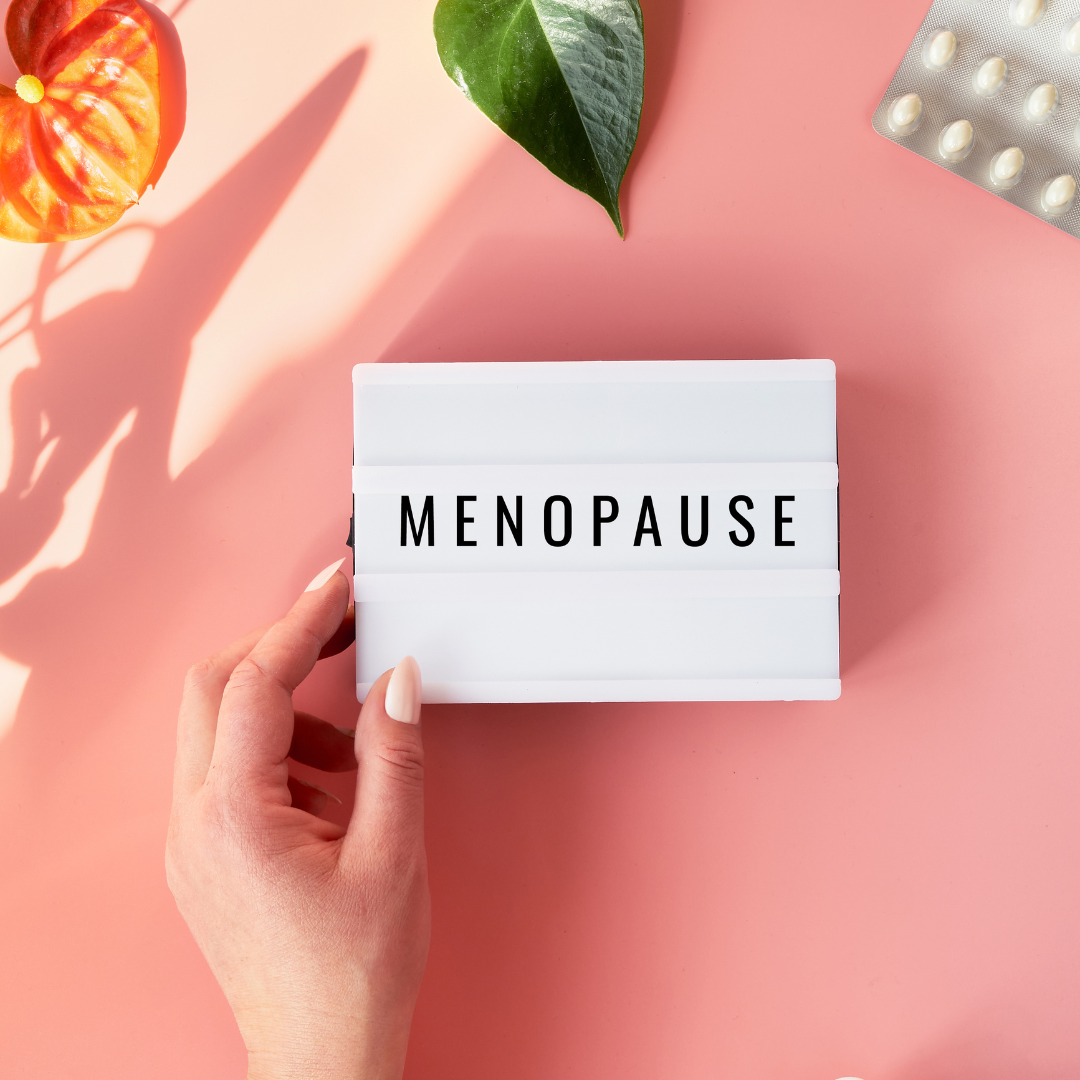 Une main de femme tient une feuille sur laquelle est écrit le mot ménopause