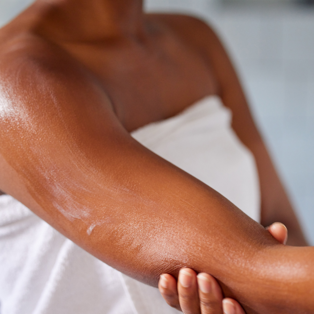 Une femme met de la crème sur son bras