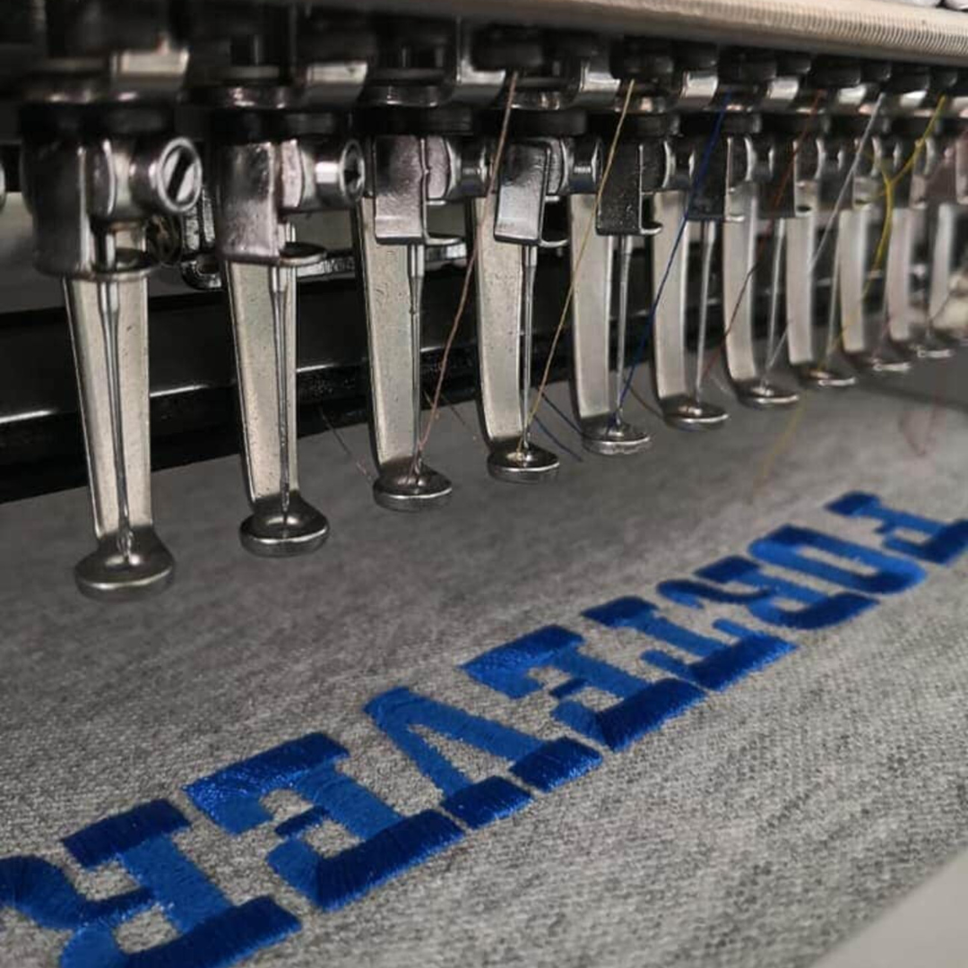 Close-up of needles sewing logo lettering