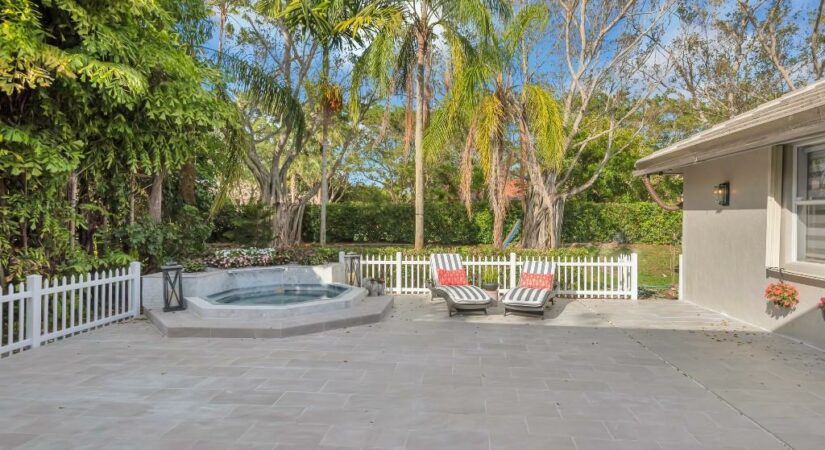 Backyard patio with a hot tub, lounge chairs, and greenery