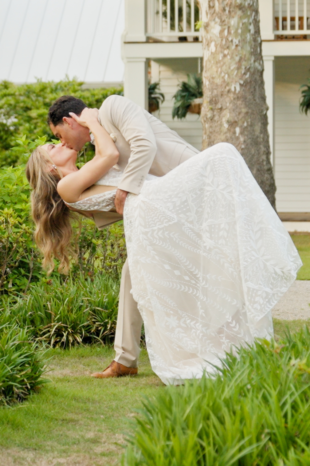groom dipping his bride in front of a manor house