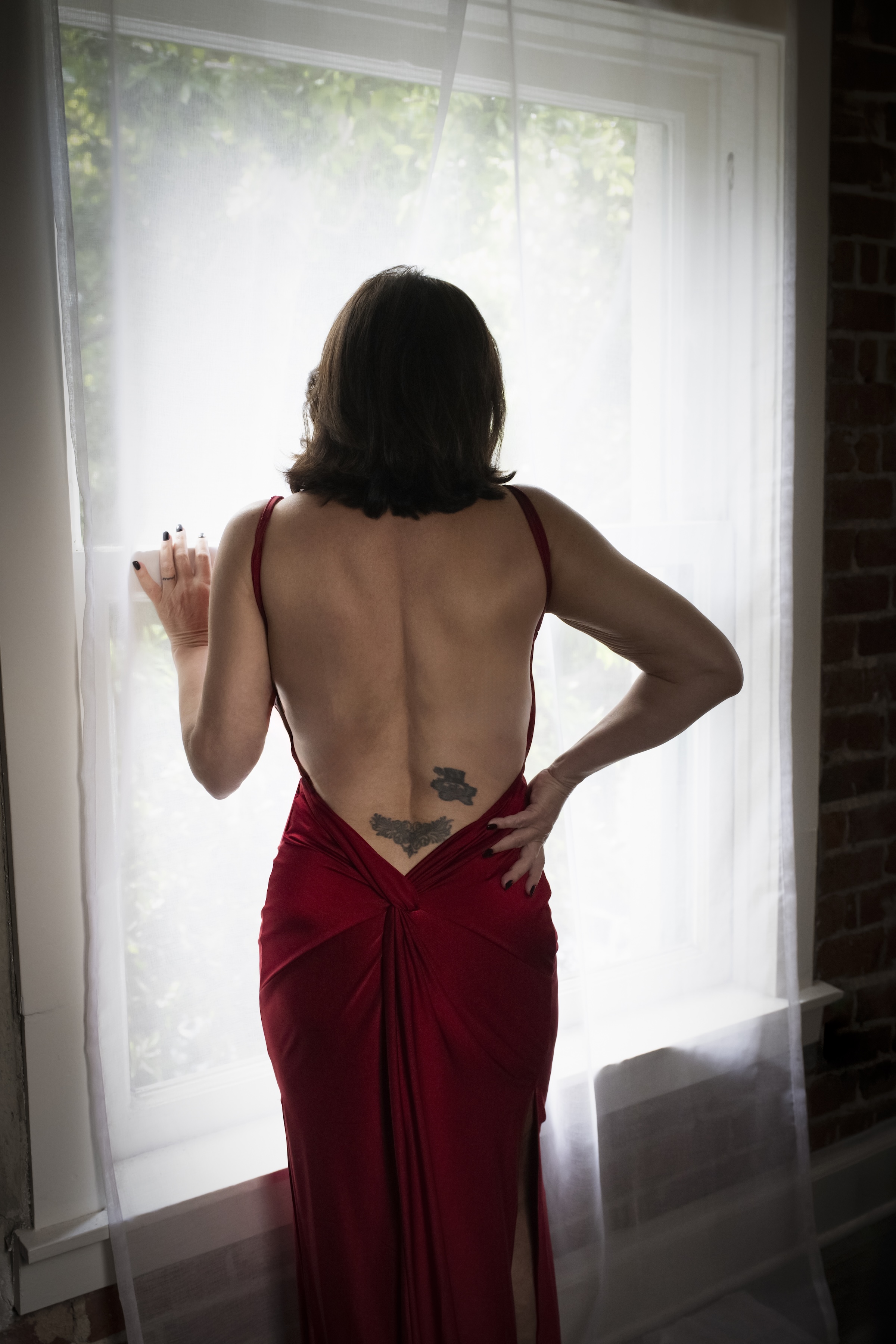 woman in red dress by window