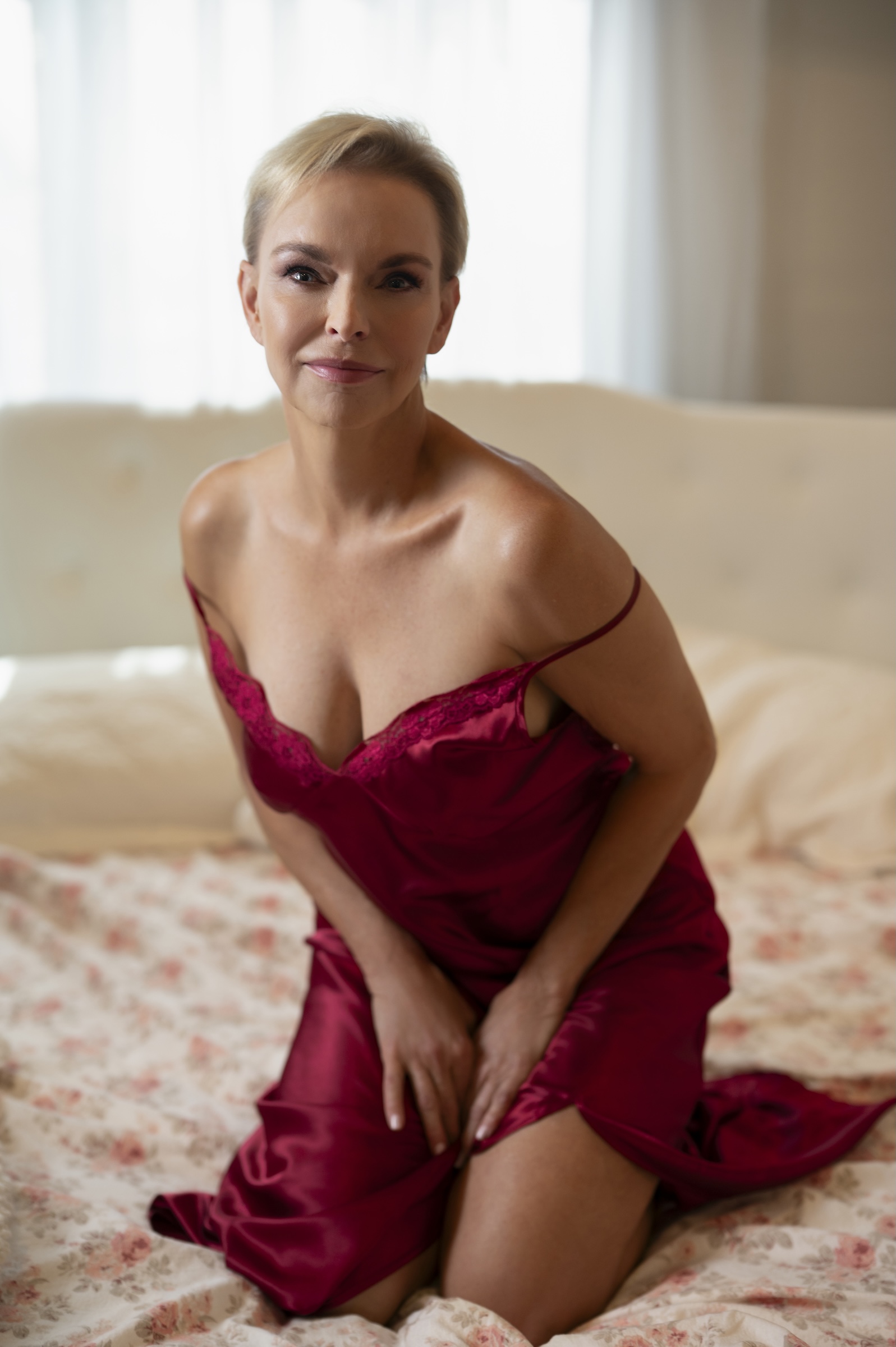 Blonde woman boudoir image with red nightgown on bed