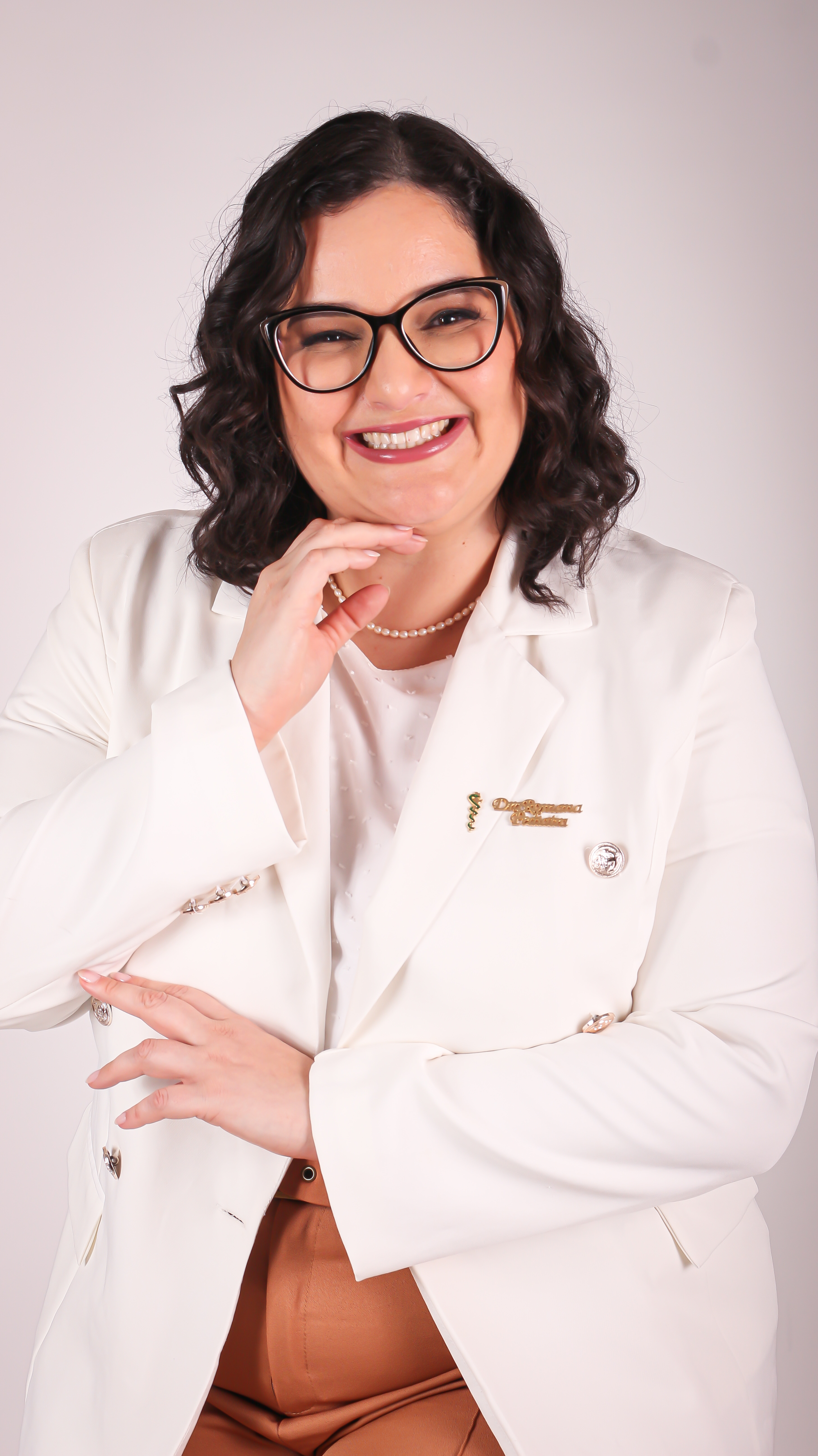 Dra. Romana Medeiros sorrindo, de óculos e blazer branco