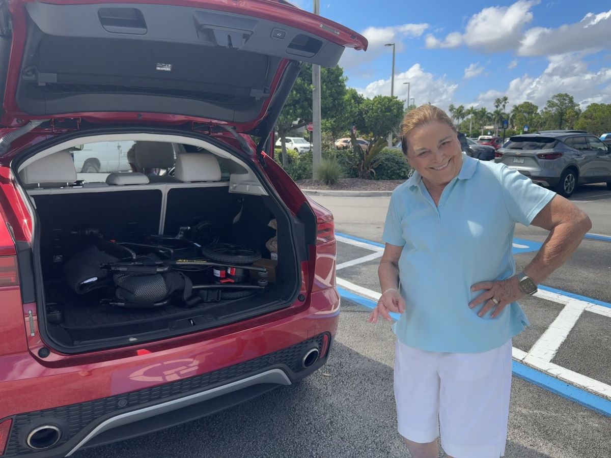 A customer beside her open trunk with the folded Cricket LT Carbon inside