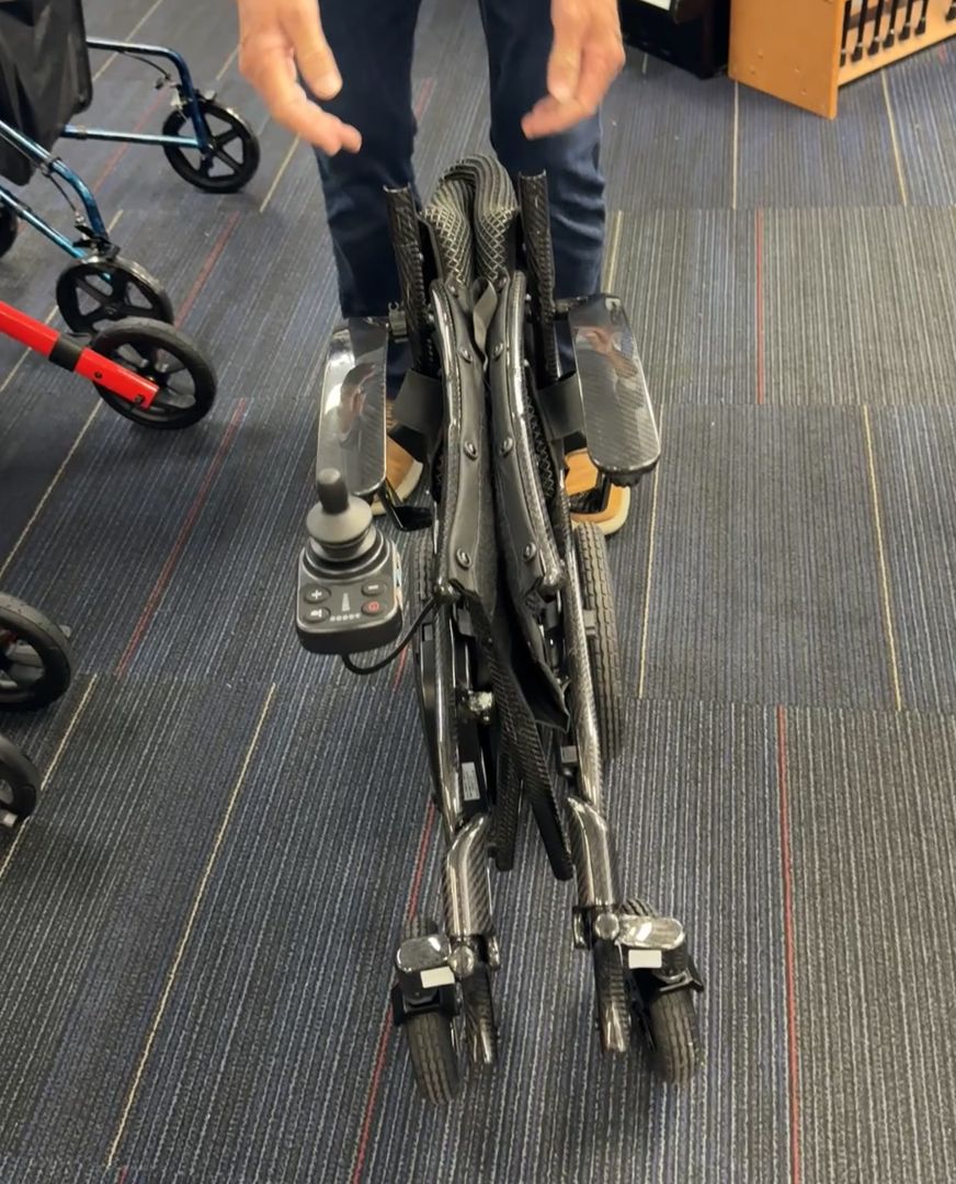 The folded Cricket LT Carbon standing on its own wheels in our showroom