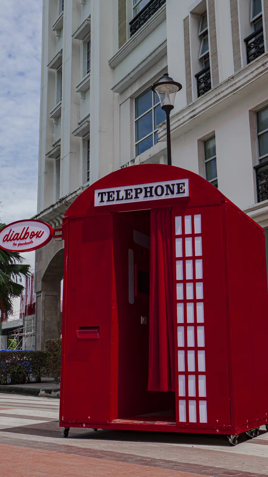 The red Dialbox telephone booth with its oval dialbox sign, standing on a Davao street